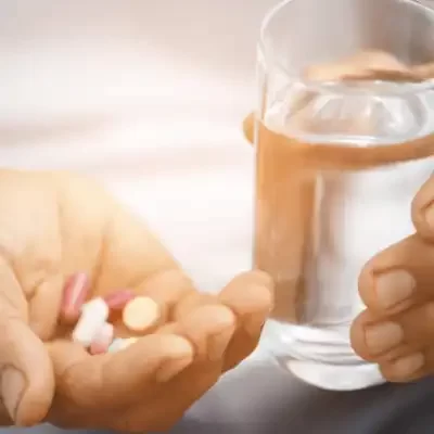 Assist clients with medication hand holding pills and glass of water